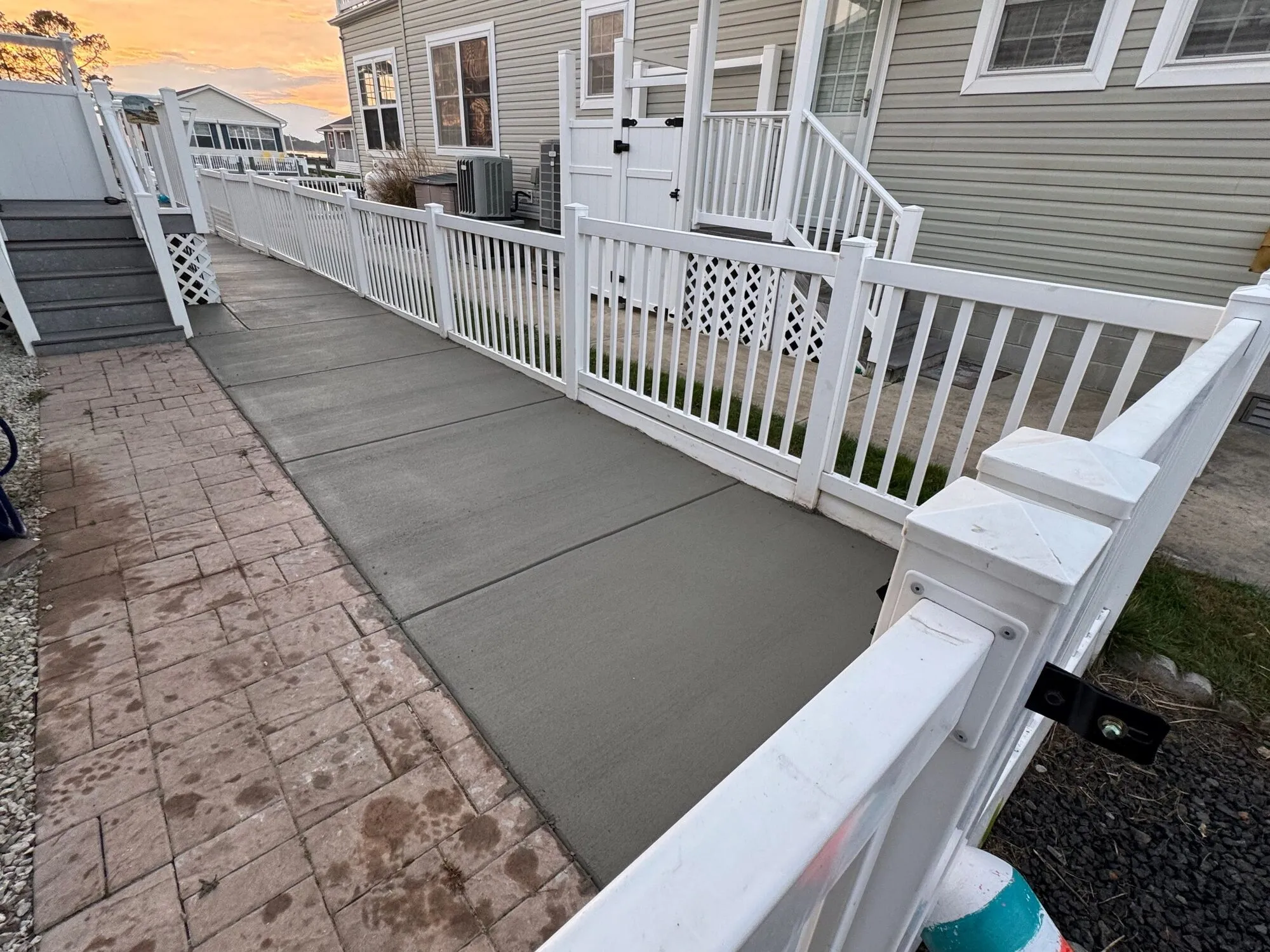 New concrete walkway beside a white vinyl fence