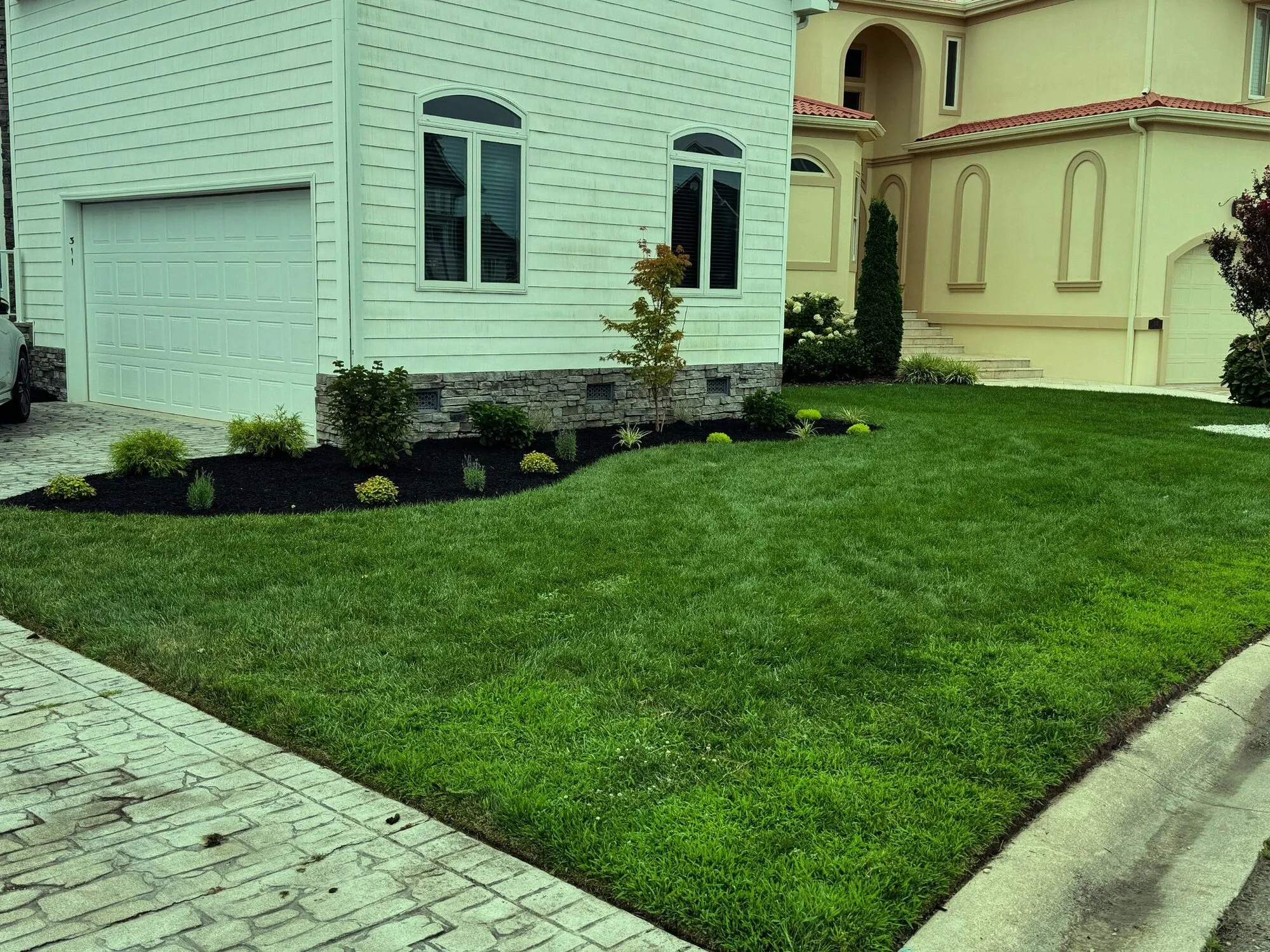 Freshly installed sod lawn with new mulched planting beds in front of a home